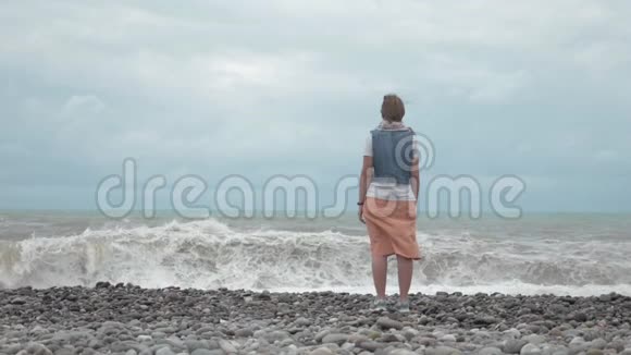 海滩上的年轻女孩看着大海的巨浪乔治亚视频的预览图