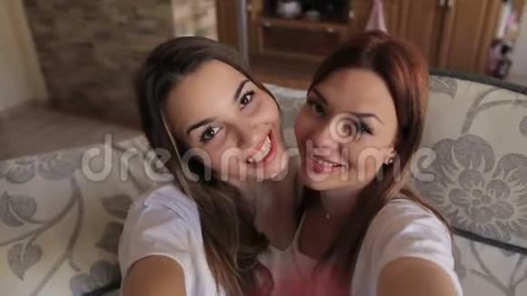 两个幸福的姐妹坐在沙发上自拍视频的预览图