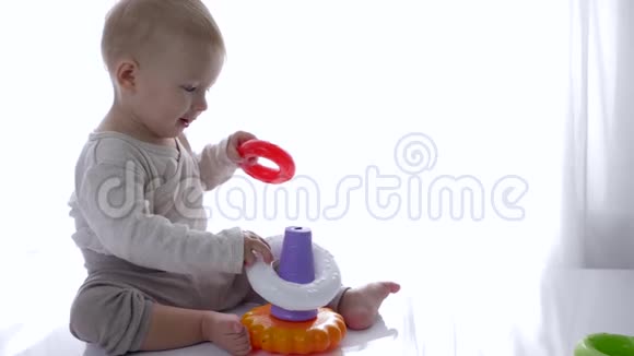 微笑漂亮的婴儿在明亮的室内玩教育玩具金字塔视频的预览图