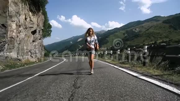 穿裙子的年轻金发旅游女孩在山里的路上视频的预览图