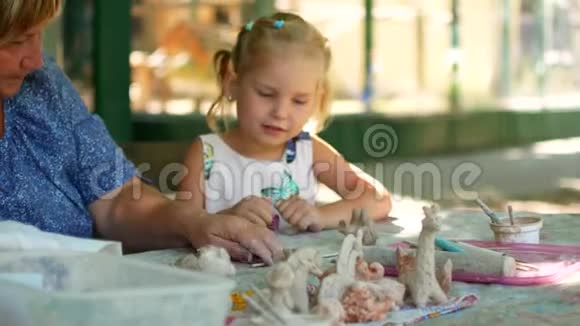 一个小女孩在祖母的帮助下雕刻泥塑视频的预览图