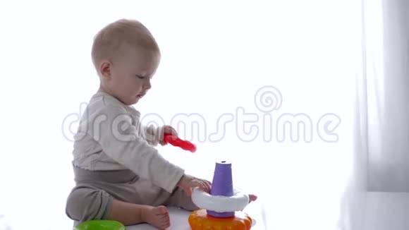 可爱的幼儿在明亮的房间里玩教育玩具金字塔视频的预览图
