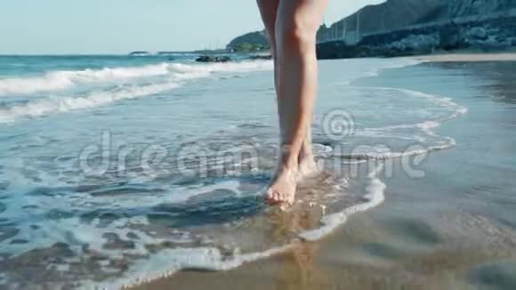 女性的腿在水波上行走苗条的女性腿在沙滩上移动视频的预览图