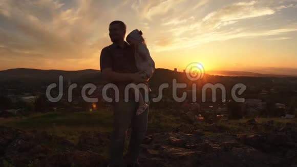 一个幸福的家庭在日落时父亲正把女儿抱在怀里视频的预览图