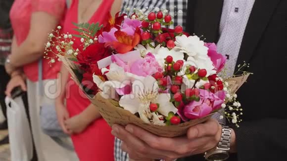 英俊的商人拿着花穿西装的新郎拿着一束花婚礼优雅的男人视频的预览图