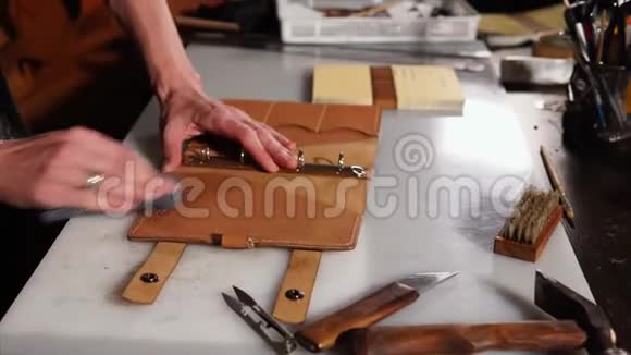 在他的工作室里一个人在桌子上为一本书揉着成品皮革封面艺术视频的预览图