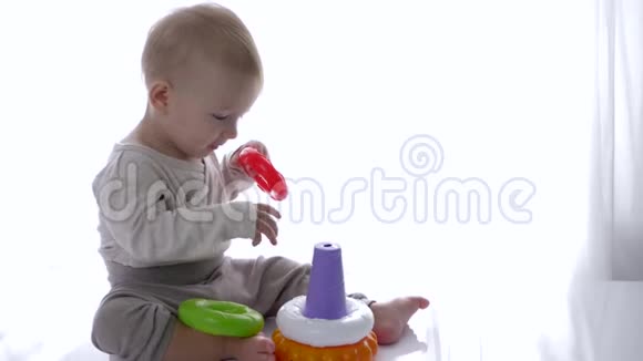 可爱的小男孩在明亮的房间里玩教育玩具金字塔视频的预览图