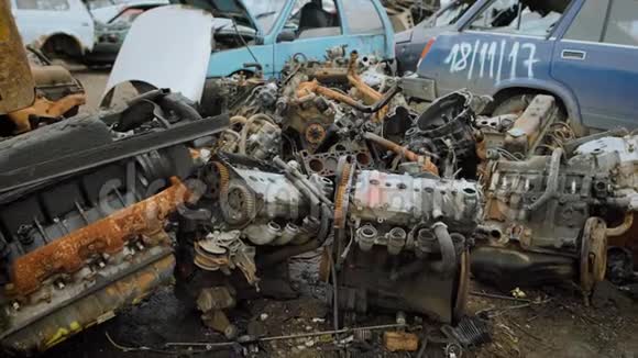 旧的破车发动机在汽车废料处理厂的一个地区的地面上堆积如山视频的预览图