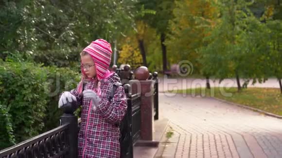 女孩子沿着一条漂亮的铁栅栏沿着小路走一个女孩放学后在公园里散步视频的预览图