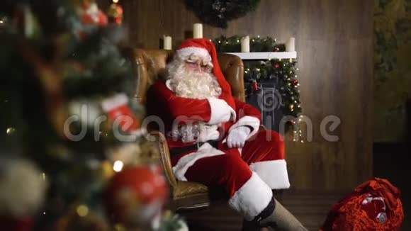 圣诞老人用玩具和灯在圣诞树附近拉出旧的红绸相册视频的预览图