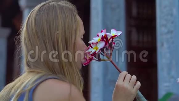 在PhuQuoc岛上的一座波德寺里女人和她的儿子嗅着佛兰吉帕尼的花朵视频的预览图