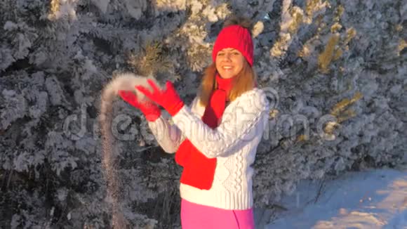 美丽的女人扔雪站在雪下享受冬天的户外活动视频的预览图