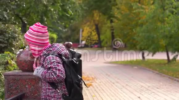 女孩子沿着一条漂亮的铁栅栏沿着小路走一个女孩放学后在公园里散步视频的预览图