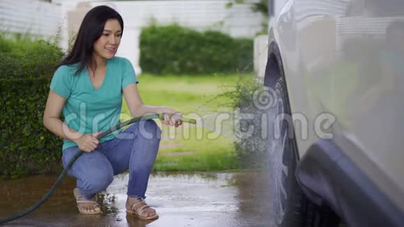 女人用水管冲洗她的汽车车轮视频的预览图