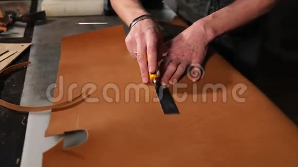 师傅正在用金属规则和锋利的刀切一块棕色的皮肤视频的预览图