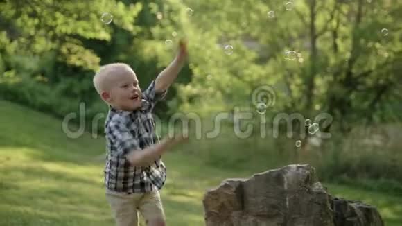 快乐的小男孩在夏天公园吃肥皂泡慢动作全高清视频的预览图
