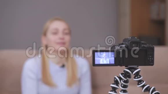 女视频录像机在坐在沙发上时在镜头前拍摄vlog视频的预览图