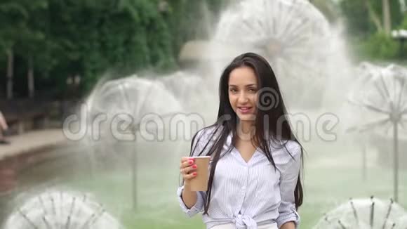在喷泉背景上喝咖啡的女孩视频的预览图