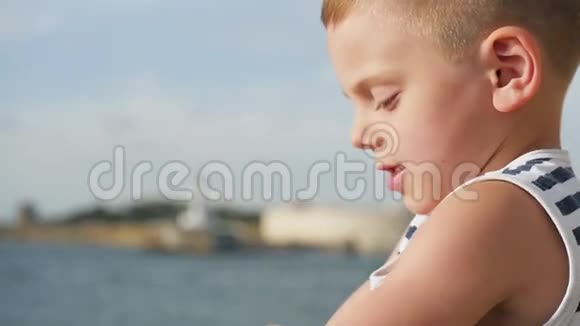 一个穿着条纹衬衫的小男孩手里拿着一副望远镜坐在大海前视频的预览图