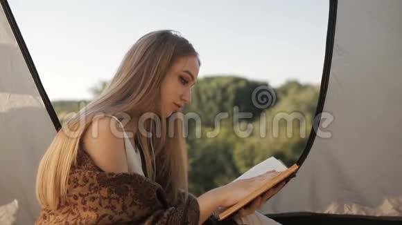 年轻女子在帐篷里休息看书了解大自然视频的预览图