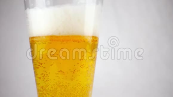 啤酒杯特写在一杯啤酒泡沫和缓慢运动的气泡中视频的预览图