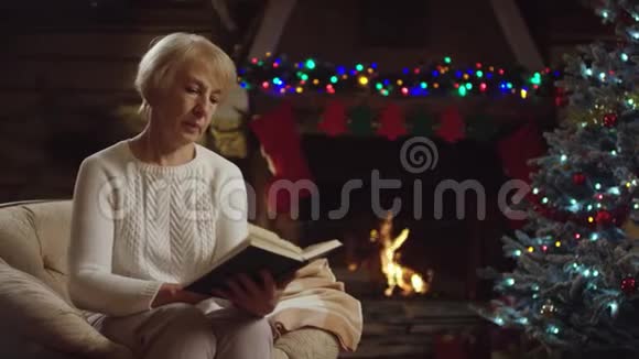 老妇人在圣诞树旁看书视频的预览图