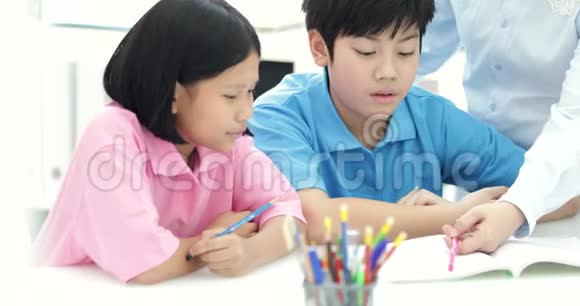 年轻的亚洲教师在课堂上帮助年轻的学生关闭视频的预览图