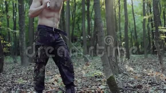 英俊的长胡子的人带着斧头在森林里散步4K视频的预览图