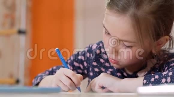 书桌前的一个小女孩画了一支蓝毛毡笔视频的预览图