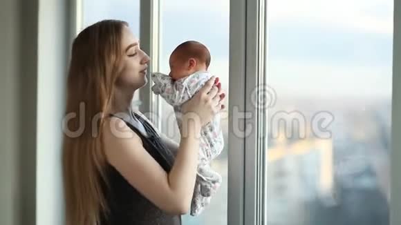 年轻的母亲和一个新生的女儿站在窗户附近视频的预览图