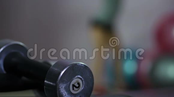 蹲在健身房的女人放松的剪影做运动的哑铃特写视频的预览图