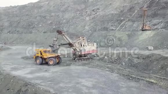 挖掘机和自卸汽车在灰色采石场装载石矿采矿业库存重型挖掘挖掘机装载视频的预览图