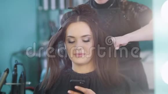 年轻的黑发美女在美容院化妆师化妆理发师做造型视频的预览图