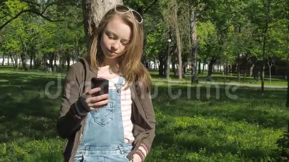 公园里有电话的女孩一个带着手机在新鲜空气中的少女有雀斑的漂亮女孩视频的预览图