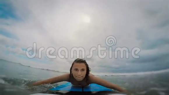 巴厘岛海洋年轻的黑发女人穿着白色的卡普尼克在冲浪板上女孩试图抓住一个波浪那个女人视频的预览图