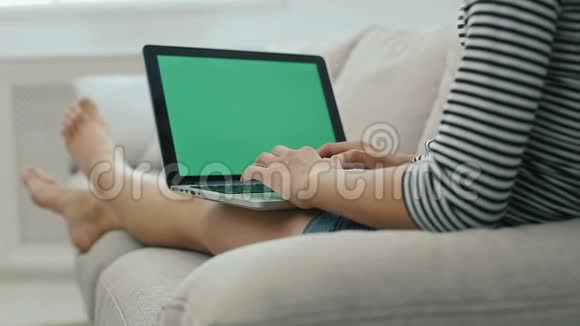 美丽的少女在沙发上用笔记本电脑和上网放松视频的预览图