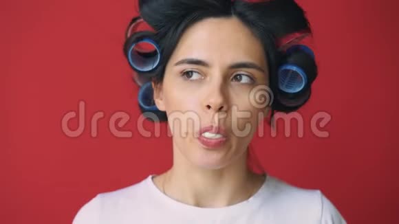 头上戴卷发器红色背景上吹口香糖的女孩视频的预览图