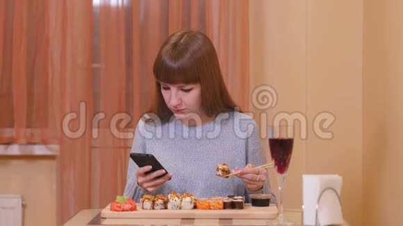 漂亮女孩吃寿司拿着电话视频的预览图