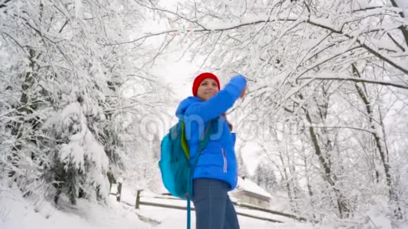女人爬上白雪覆盖的山上转过身来微笑着向某人挥手晴朗晴朗的霜冻天气视频的预览图