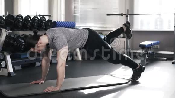 肌肉发达的年轻人在健身房里做单腿木板视频的预览图