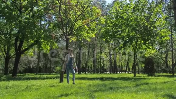 一个少年正在公园里散步一个穿着工作服带着白色袋子的少女美丽的女孩在大自然中行走视频的预览图