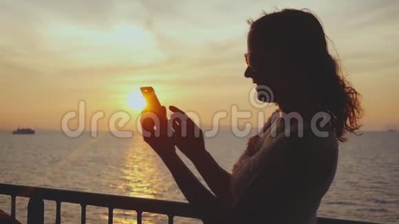 女孩的剪影使用手机在游轮旅行在惊人的日落慢动作1920x1080视频的预览图