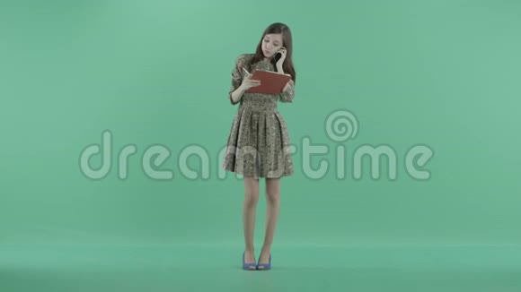 一个漂亮的女孩拿着红色的剪贴板在电话里说话视频的预览图