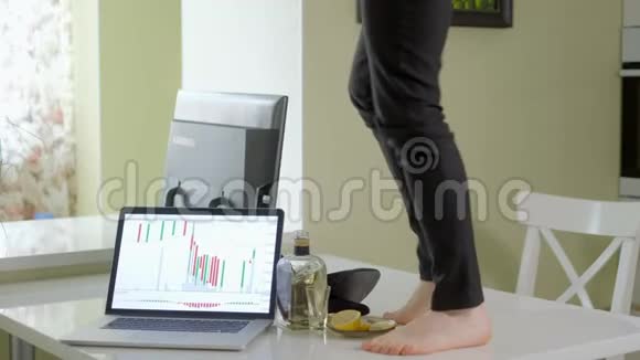 一个醉醺醺的女商人在桌子上跳舞在桌子上电脑上跳舞还有一瓶醇酒他把它从桌子上拿下来视频的预览图