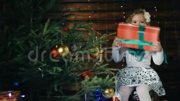 小女孩坐在圣诞树下享受礼物视频的预览图