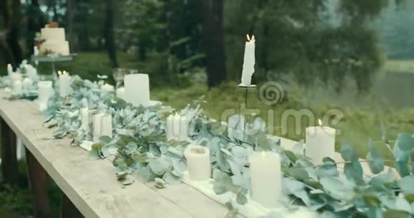 多雾的树林里浪漫约会的可爱装饰蜡烛树叶鲜花和美丽的带浆果的双层蛋糕视频的预览图