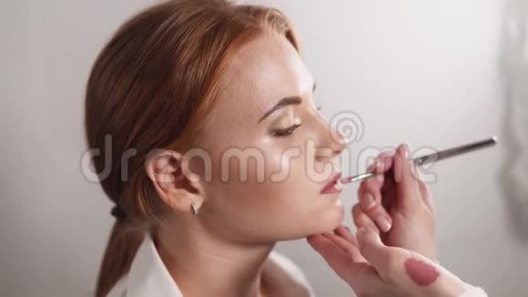 化妆师正在一个工作室里给模特的嘴唇涂口红视频的预览图