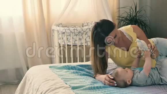 可爱的妈妈在床上和宝宝玩软玩具视频的预览图