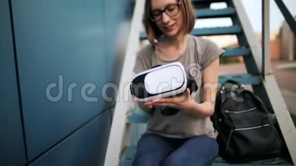 微笑的年轻女孩留着短发晚上在蓝色背景上戴着虚拟现实眼镜虚拟现实视频的预览图