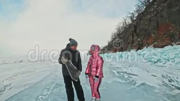 在冰封的湖面上年轻夫妇在冬天散步时玩得很开心爱情故事恋人们留着浮冰视频的预览图